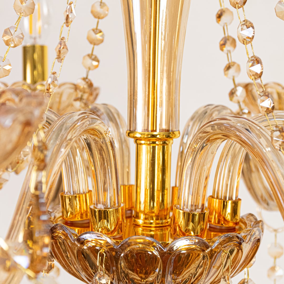 Closeup of golden crystal chandelier showing detailed beads and curved arms perfect for luxury ceiling lighting.