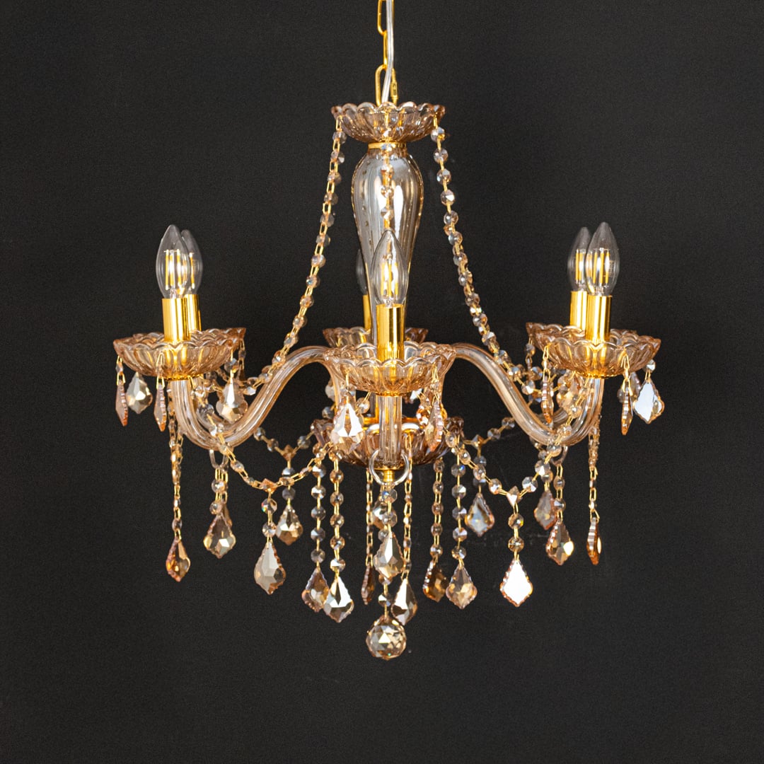 Golden crystal chandelier with ornate detailing shown on black background ideal for premium home ceiling decor.