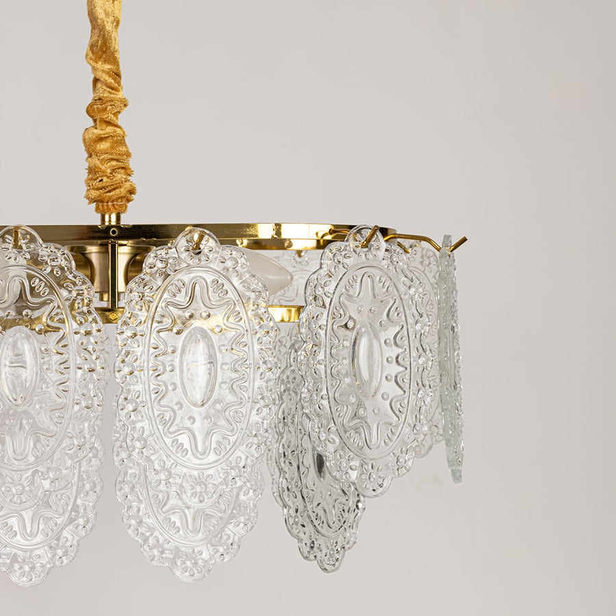 Closeup of gold metal chandelier showing ornate carved glass detailing and shimmering accents ideal for luxurious vintage interior lighting.