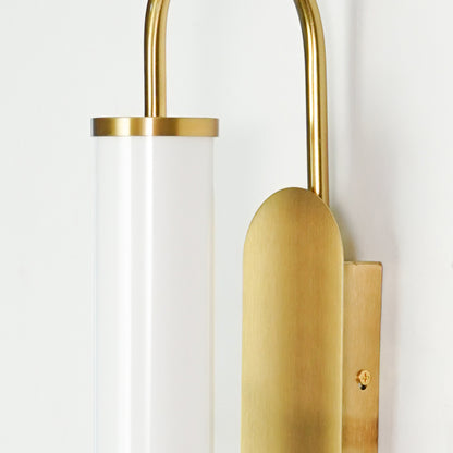 Closeup image of gold metal wall light with frosted glass tube shade for modern luxury wall decor.