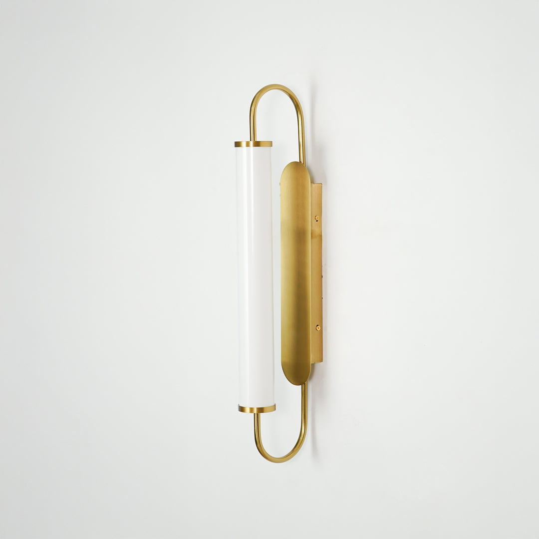 Gold metal wall light on white background with frosted glass shade for elegant minimalist interior decor.