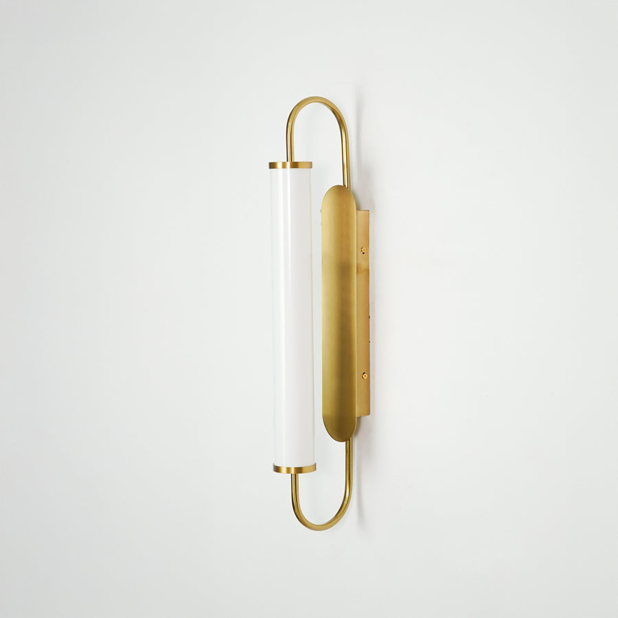 Gold metal wall light on white background with frosted glass shade for elegant minimalist interior decor.