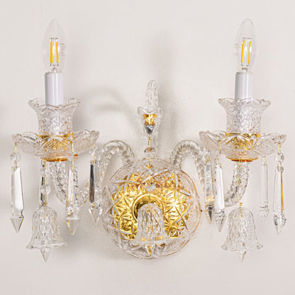 Closeup of gold and clear crystal wall light with detailed droplets and ornate arms perfect for luxury wall decor.