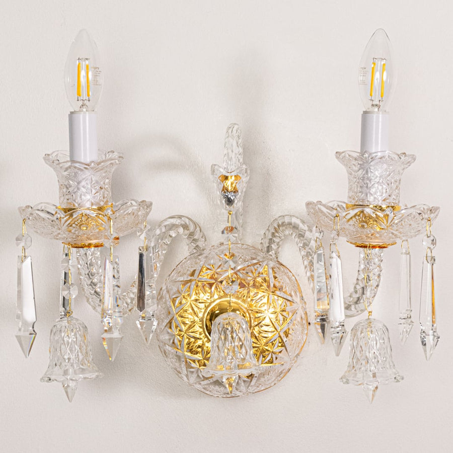 Closeup of gold and clear crystal wall light with detailed droplets and ornate arms perfect for luxury wall decor.
