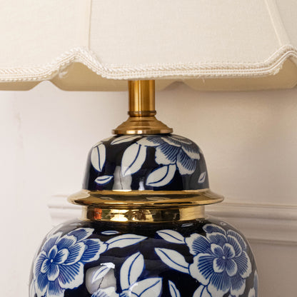 Blue floral ceramic table lamp showcasing intricate hand painted craftsmanship with brass accents and fabric shade design.