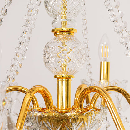 Closeup of gold metal crystal chandelier with detailed crystal drops and curved arms perfect for luxury ceiling decor.
