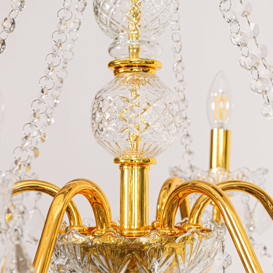 Closeup of gold metal crystal chandelier with detailed crystal drops and curved arms perfect for luxury ceiling decor.
