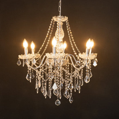 Silver metal crystal chandelier glowing warmly on black background creating a dramatic luxury ceiling feature.