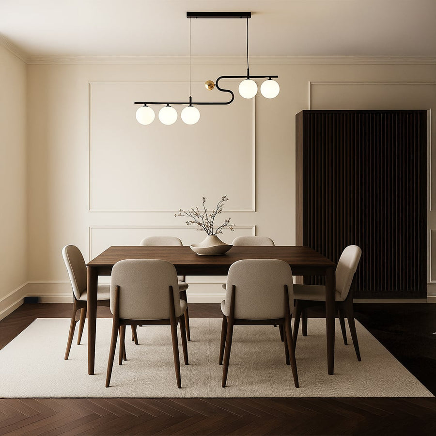 A sculptural black and gold chandelier shining softly above a neutral dining table arrangement adding refined warm LED lighting and sophisticated décor.
