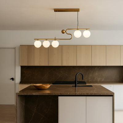 Modern gold ceiling chandelier with white globe lights in a kitchen background with lights on perfect for modern lighting décor and interior design.