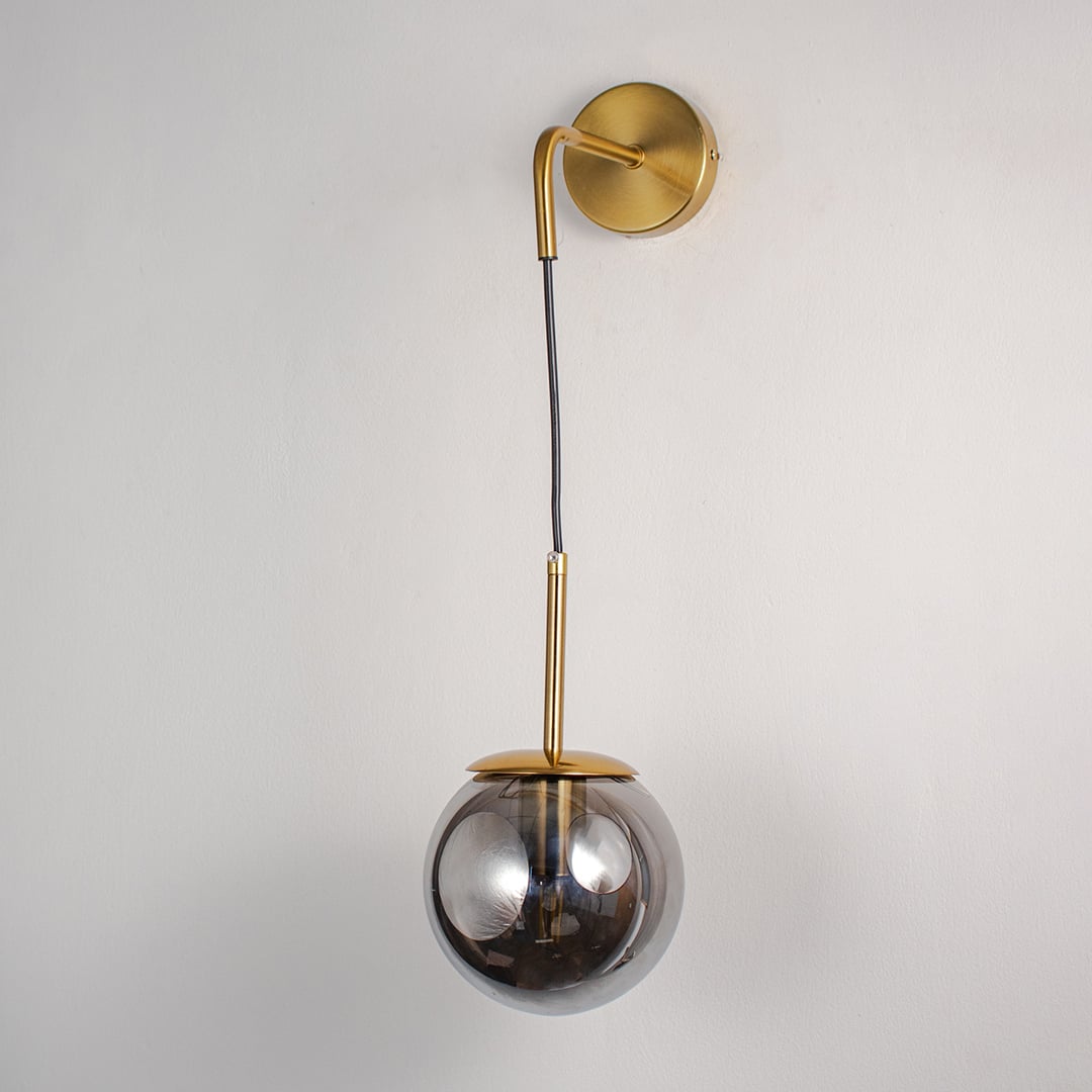 Smoked glass globe wall lamp with gold metal base light off on white background elegant wall lighting for living and dining.
