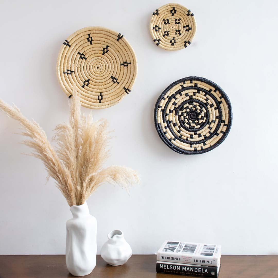 Handwoven wall basket styled on a living room wall above a wooden table with ceramic vases adding a modern rustic aesthetic.
