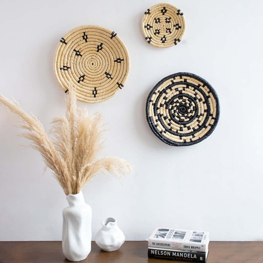 Handwoven wall basket styled on a living room wall above a wooden table with ceramic vases adding a modern rustic aesthetic.