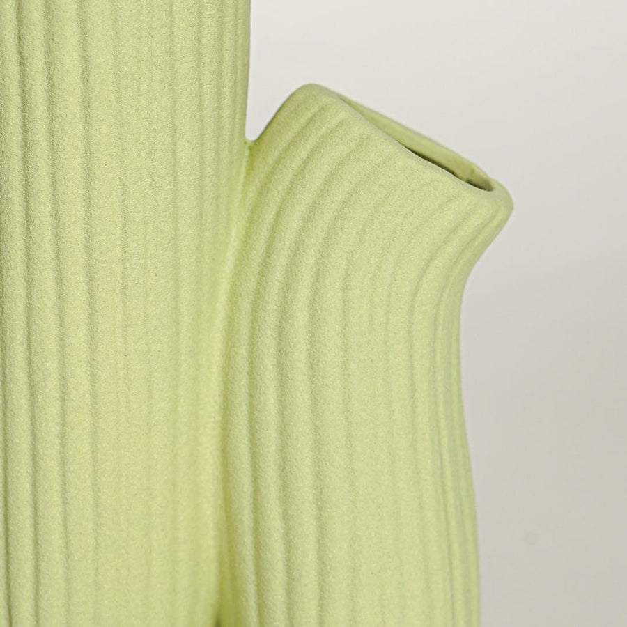 Close view of light green ceramic vase showing ribbed texture matte finish and contemporary sculptural styling.
