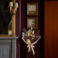 Dried floral arrangement styled in classic interior with framed artwork adding rich color and elegant focal point to home Decor.