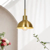 Modern gold metal pendant light hanging above table for stylish dining room and luxury interior decor styling.