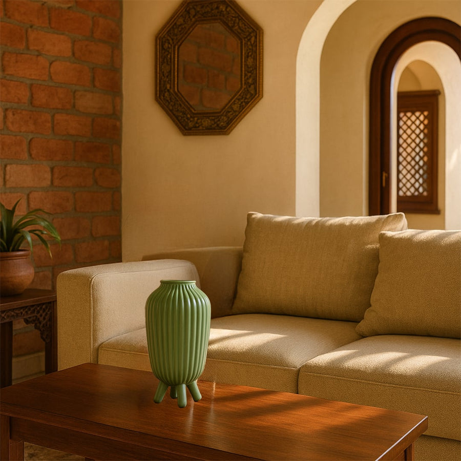 Green ribbed vase displayed in a styled setting adding a modern touch with its tall shape and tripod base highlighted in gentle natural lighting.