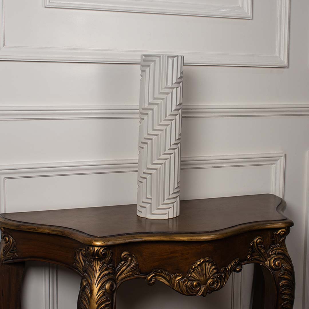 Tall white geometric ceramic vase with embossed linear pattern displayed on a plain white background showcasing its elegant modern form.