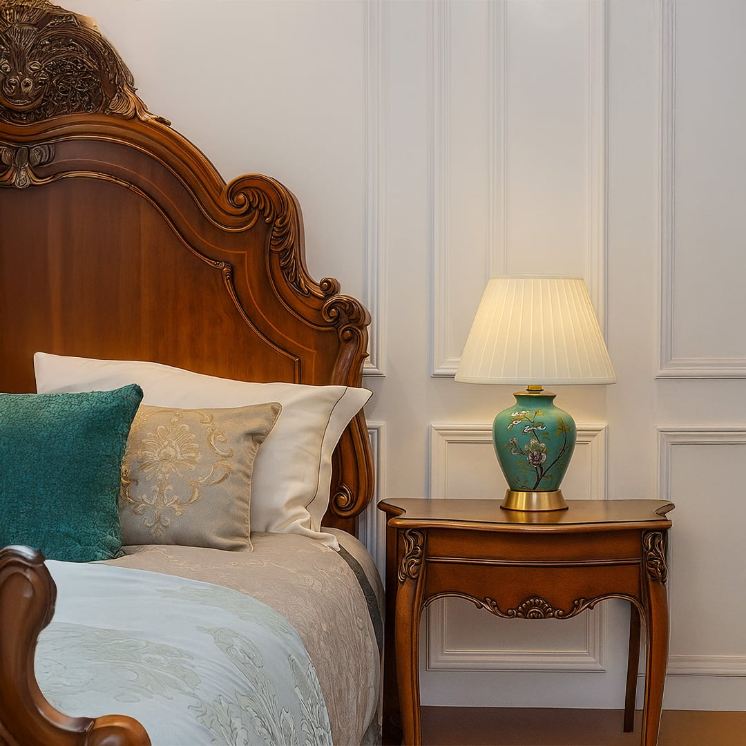 Green ceramic table lamp with floral hand-painted design and pleated fabric shade adding elegance to bedroom decor.