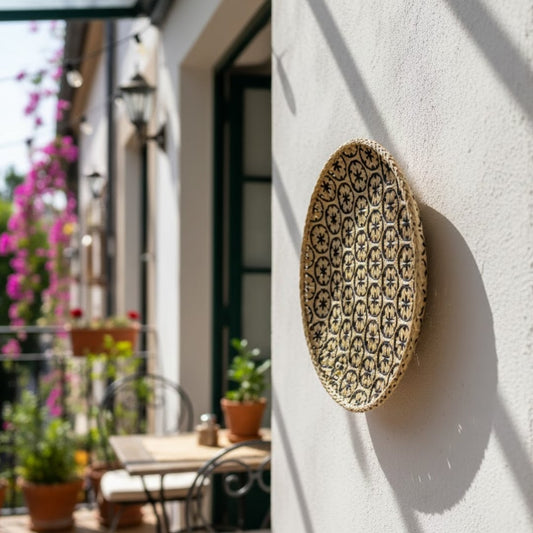 Handcrafted round wall decor in natural fiber finish mounted on outdoor wall near seating adding warm texture and elegant home styling.