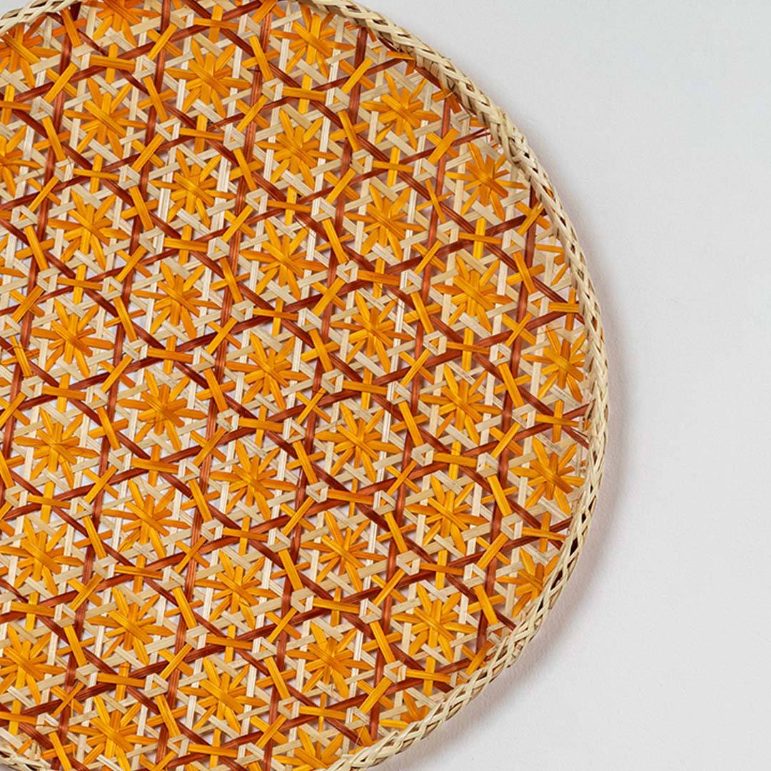 Closeup of orange woven wall basket with dense textured pattern showing fine craftsmanship natural material and vibrant decor appeal.
