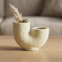 Beige ceramic flower vase with textured finish placed on wooden table for elegant modern home decor styling.