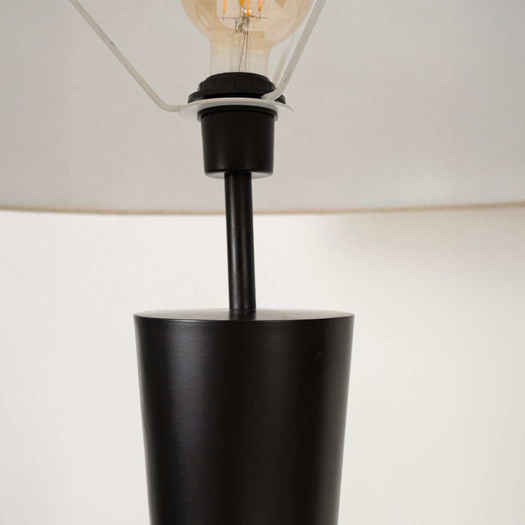 Closeup of modern floor lamp shade and upper stem showing smooth finish fabric texture and warm light spread highlighting premium craftsmanship.