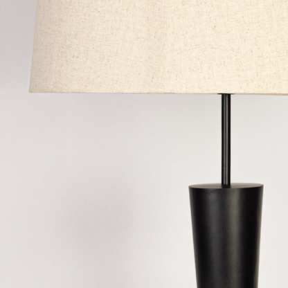 Second closeup view of modern floor lamp base and slim pole showing matte black surface solid build and elegant silhouette under soft lighting.