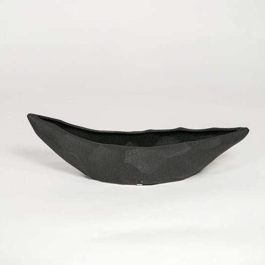 Black ceramic decorative platter with angular faceted texture isolated on clean white background for modern table decor styling.