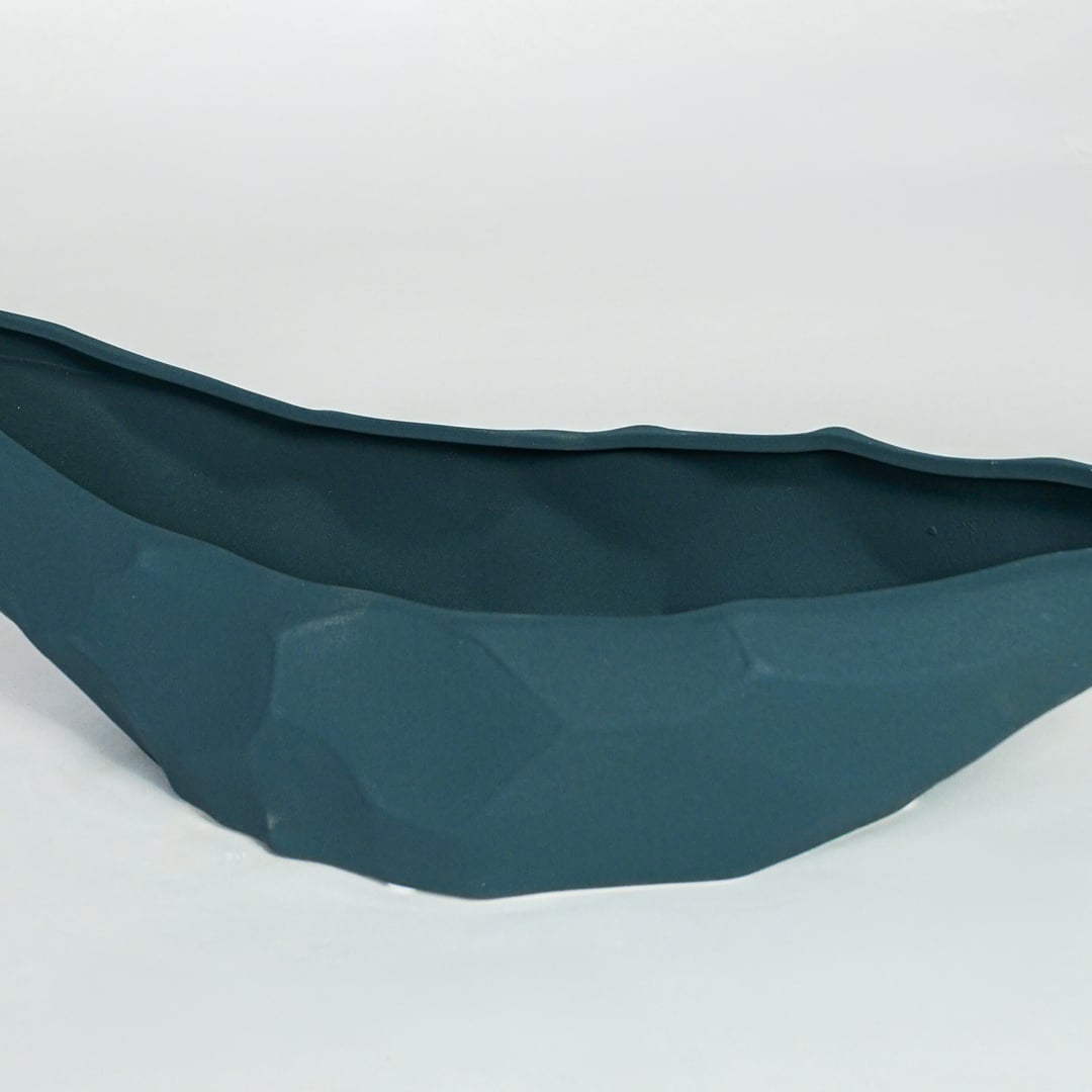 Detailed closeup of teal ceramic decorative platter showcasing faceted surface and smooth glazed finish.