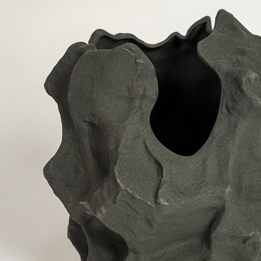 Close up view black sculptural ceramic vase showing organic textured surface matte finish decorative ceramic accent for home styling.