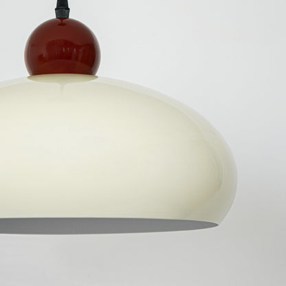 Closeup of cream pendant light with burgundy top accent for elegant modern interior decor styling.