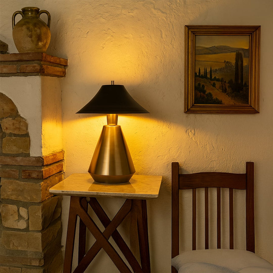 Warmly lit corner featuring a metal table lamp with a black shade on a marble-top table creating a cozy and elegant ambience.