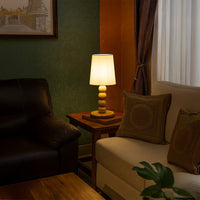 Modern table lamp with tall white shade and stacked light wood base adding warm ambient lighting that enhances stylish contemporary interior home decor settings.