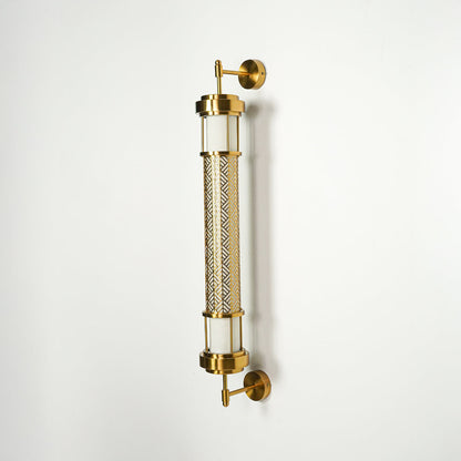 Modern gold wall sconce with cylindrical glass tubes and metal detailing on clean background perfect for contemporary interior decor lighting.