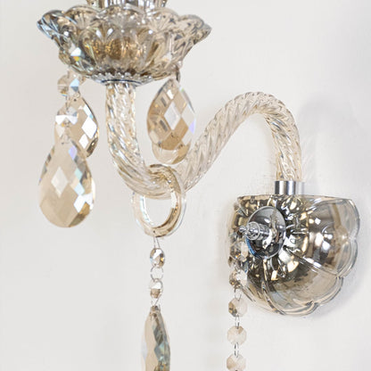 Closeup of crystal wall light with decorative glass shade and hanging crystals for luxury home interior.