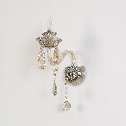 Decorative crystal wall light with glass shade and hanging crystal accents turned off on white background.