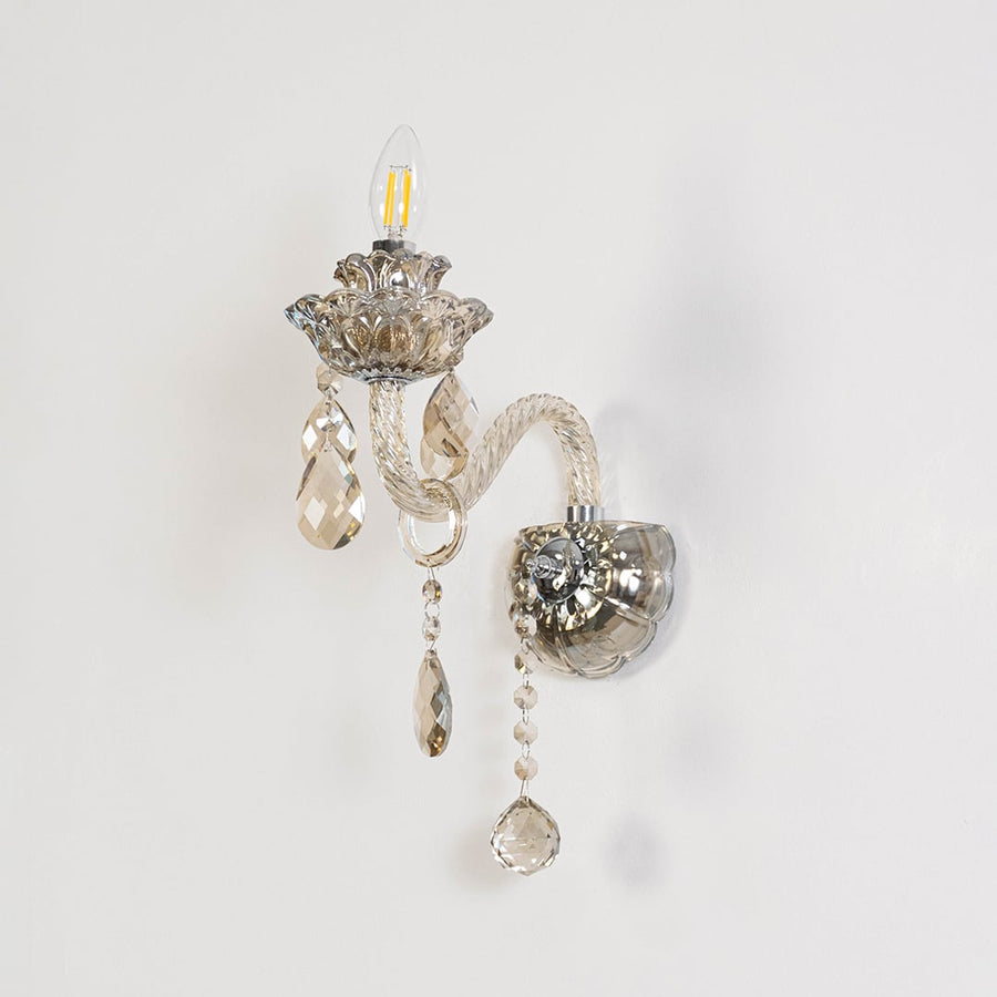 Decorative crystal wall light with glass shade and hanging crystal accents turned off on white background.