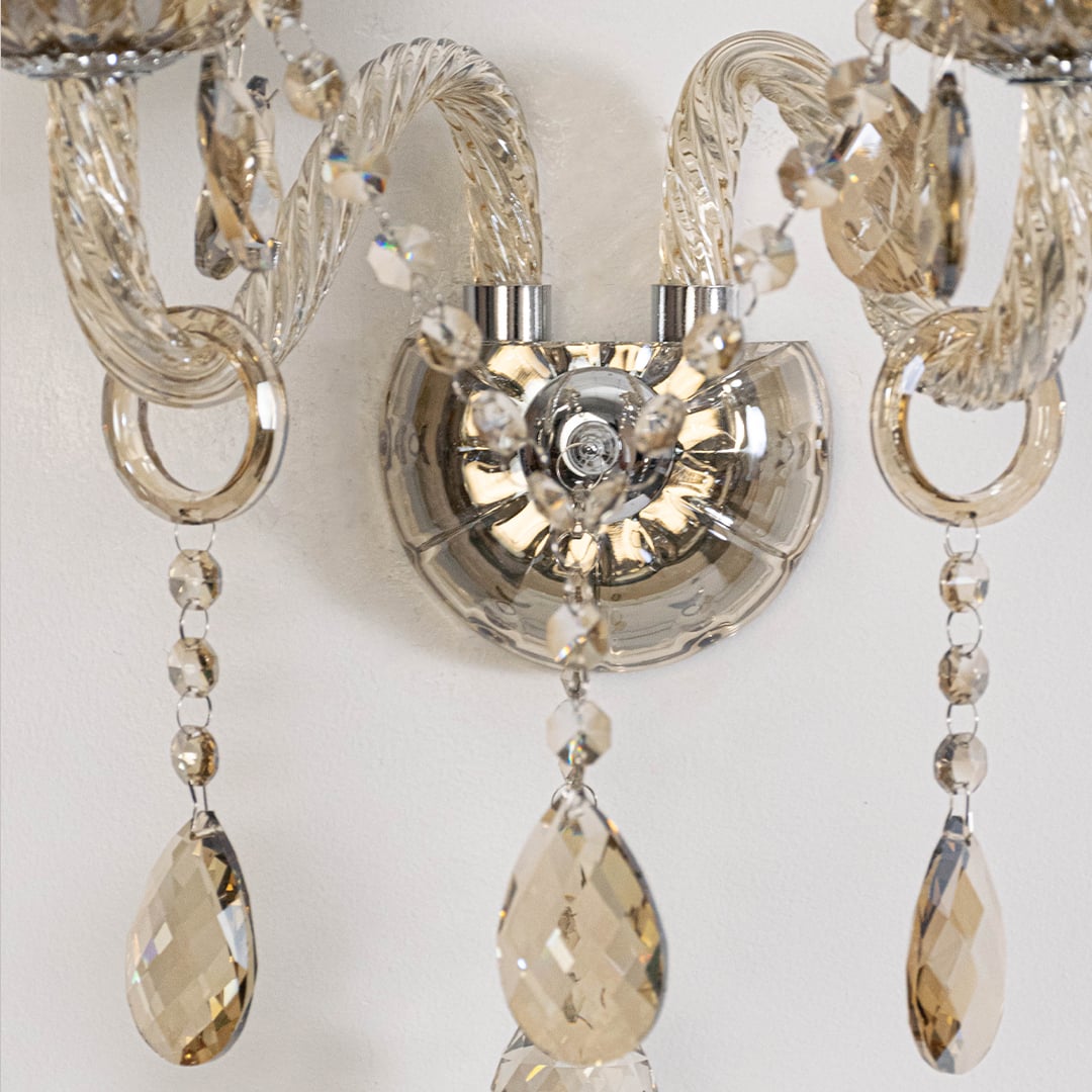 Closeup of double arm crystal wall light with detailed glass design and hanging crystal drops.