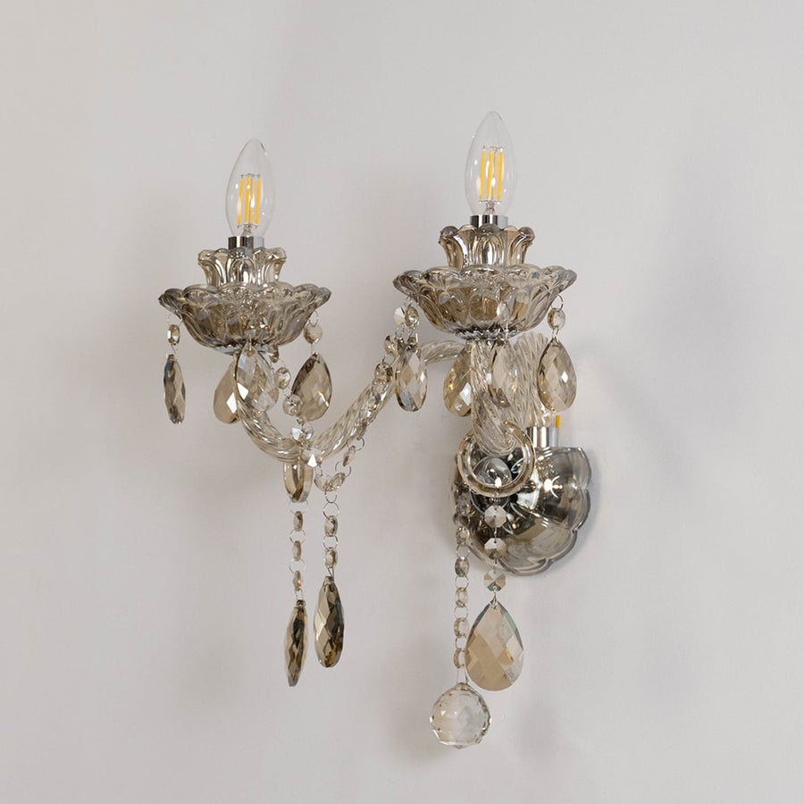 Double arm crystal wall light with glass shades and crystal accents turned off on white background.