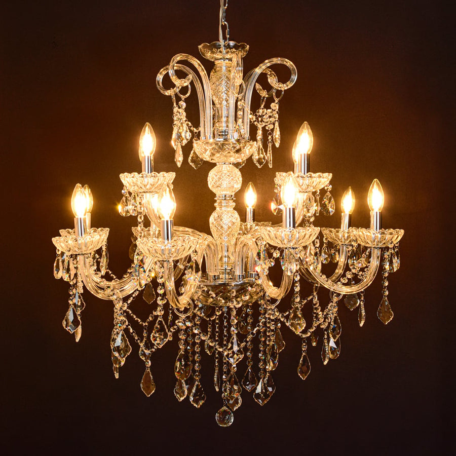 Large clear crystal chandelier glowing warmly on black background creating a dramatic luxury ceiling feature.