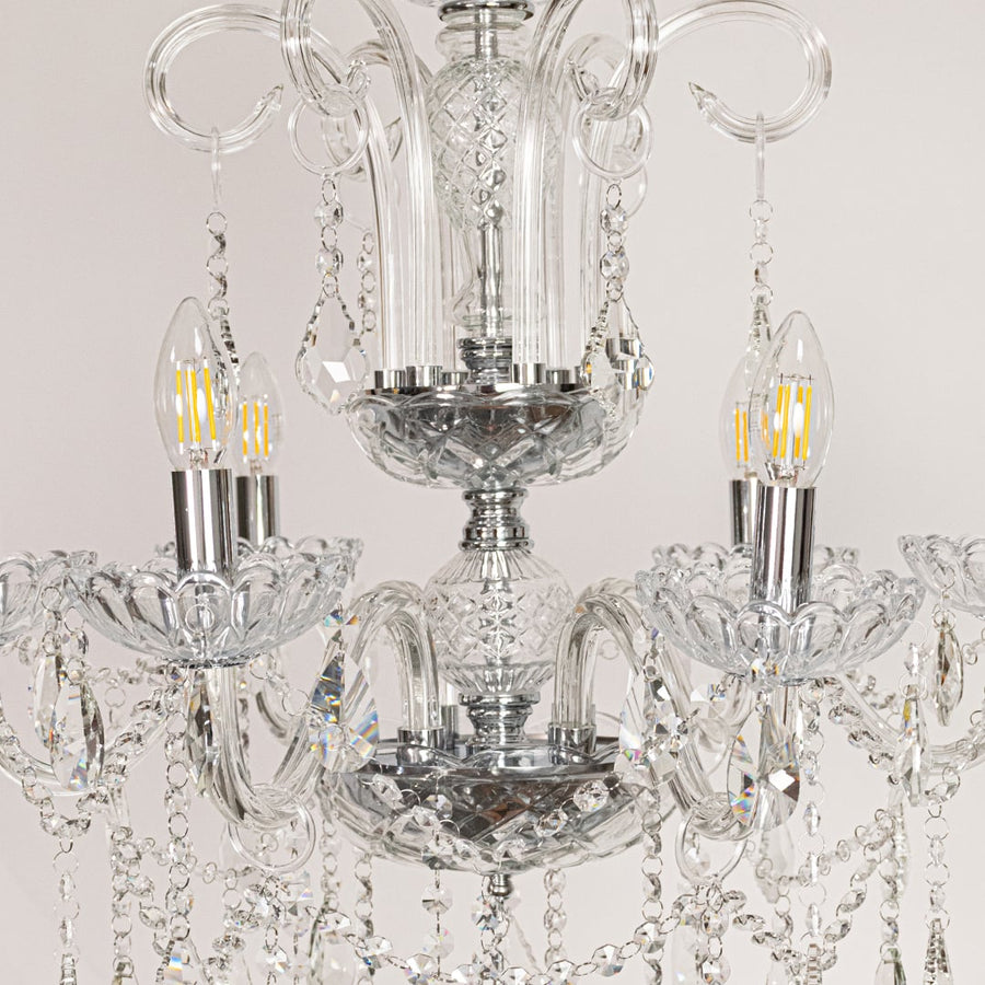 Closeup of clear crystal chandelier with detailed crystal beads and curved arms perfect for luxury ceiling lighting.