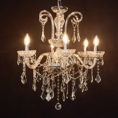 Clear crystal chandelier glowing warmly on black background creating a dramatic luxury ceiling feature.