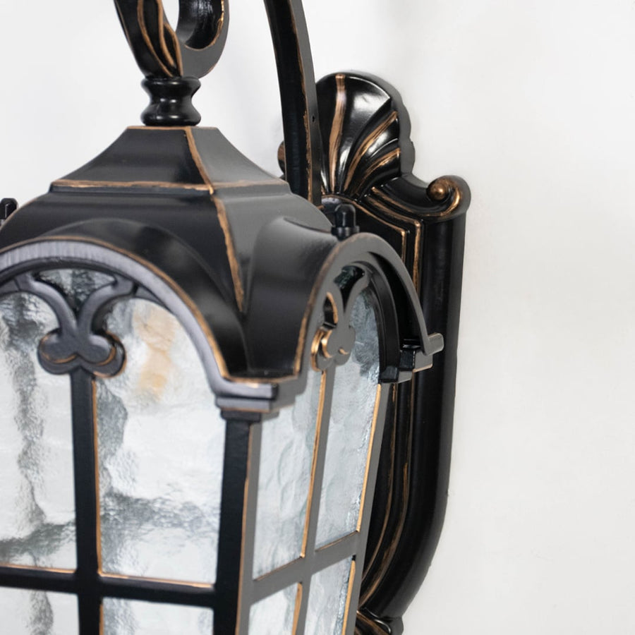 Closeup image highlights black metal frame and textured clear glass of outdoor wall lantern for durable exterior use.
