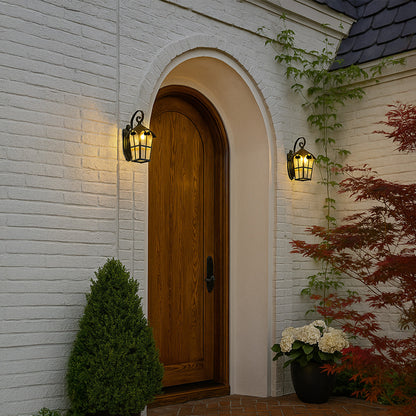 Vintage outdoor wall lantern mounted beside an arched wooden door creating warm welcoming lighting for exterior home entrance walls.