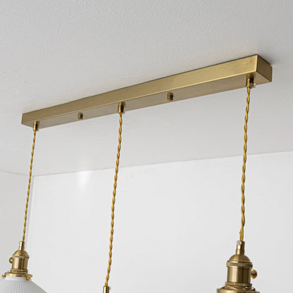 Gold metal linear ceiling canopy with decorative chains highlighting premium finish and craftsmanship.