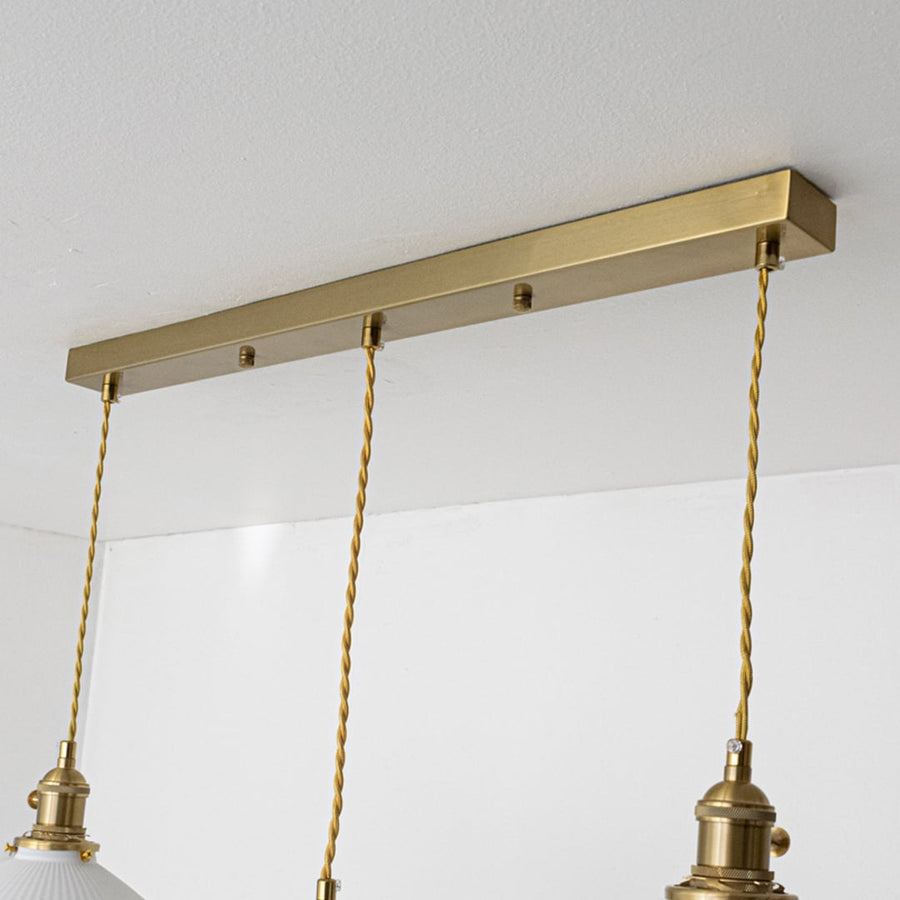 Gold metal linear ceiling canopy with decorative chains highlighting premium finish and craftsmanship.