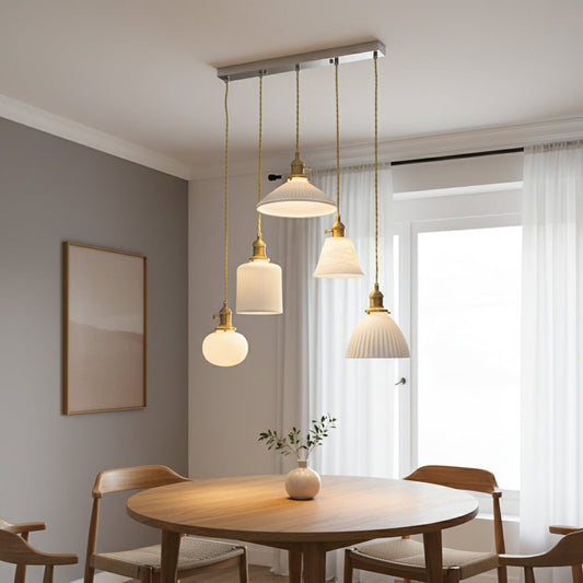 White glass and gold metal pendant lights adding elegant warmth above the dining table in interiors.