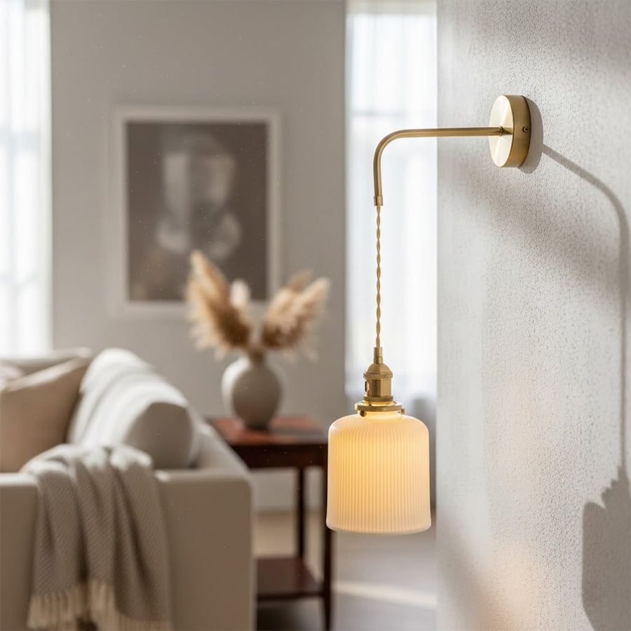 Gold metal hanging wall light lifestyle image with pleated glass shade for elegant modern bedroom decor.