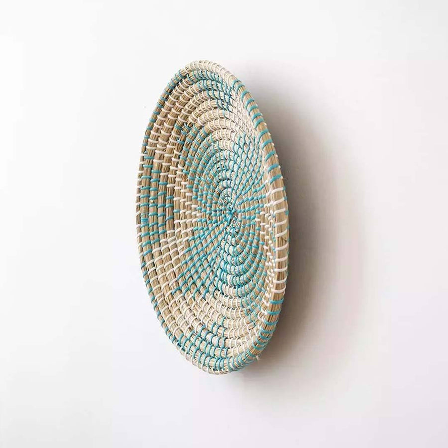 Handwoven seagrass round wall basket decor in natural beige and teal with raised woven profile shown on white background.